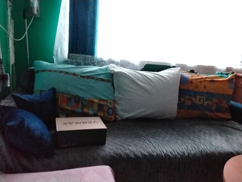 Kliento „Baldo užnešimas“ lova su spalvingomis pagalvėmis ir „Venmax“ dėžute ant lovos.