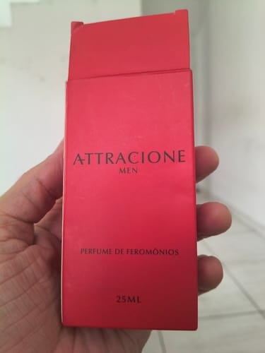 Customer's hand holding the rectangular red box of Attracione Men perfume.