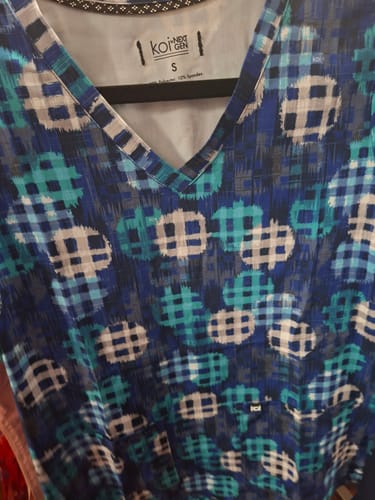 Customer's Koi 1029PR scrub top with a blue, teal, and white plaid pattern and a v-neckline.