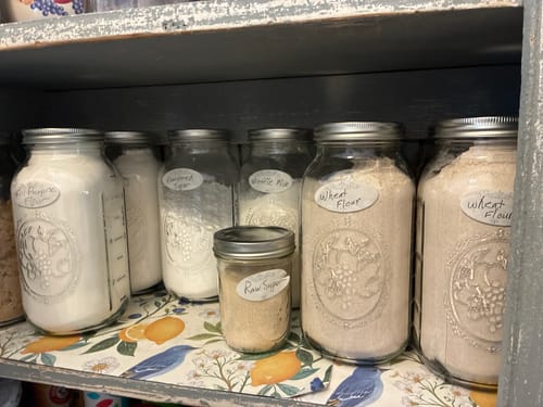 Customer's Mason Genie Vacuum Sealer Kit used on labeled glass jars filled with dry goods in a pantry shelf.