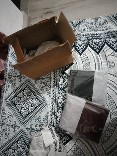 Customer's packaging for the ZIORO Spiderman wallet, showing a cardboard box and two wrapped items on a patterned bedspread.