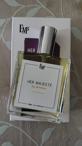 Customer's square Her Majesté Eau De Parfum bottle with a silver cap, placed in front of its branded white box.