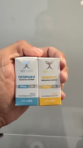 Customer's hand holding two XT Labs boxes, Primoplex and Testoplex-E, for a maintenance combo review.