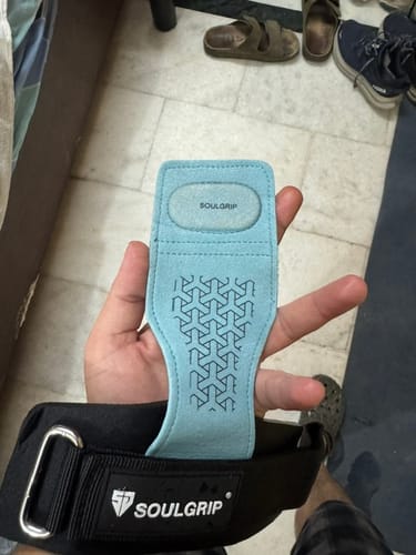 Reviewer's hand holding a blue SoulGuard lifting grip, showing the patterned palm grip and branding.