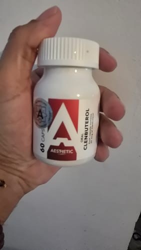 Customer's hand holding a white bottle of Aesthetic ClenX Oral Clenbuterol capsules with a red label.