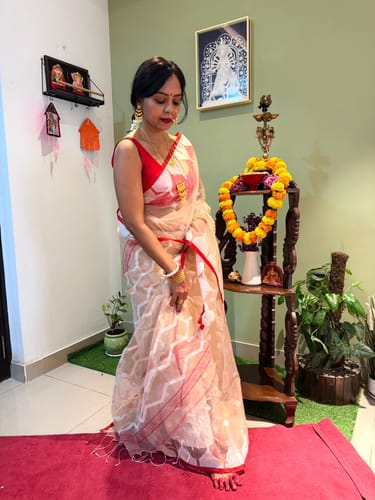 Reviewer wearing a sheer, light beige Organza Muslin Jamdani Saree with red temple border and white geometric motifs.