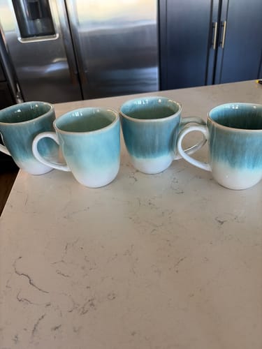 Customer's Aqua Blue Mug set on a counter, showing one paler mug and three darker blue mugs.