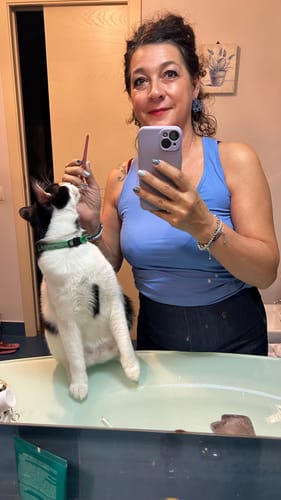 Recensione del siero BioChroma, la cliente si specchia in bagno con il suo gatto al fianco.