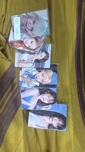 Customer's collection of five fromis_9 Glow ME photocards displayed in plastic sleeves on a textured yellow surface.
