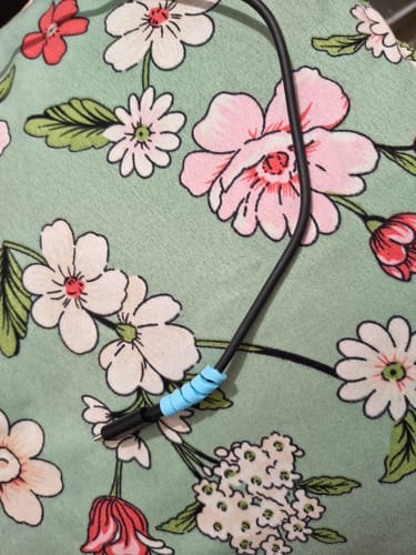 Customer's blue spiral cable protector attached to a black charging cable against a floral background.