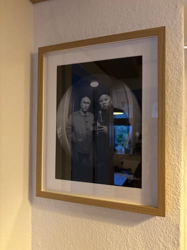 Reviewer's framed Criss Bellini art print of two figures hanging on a white wall.