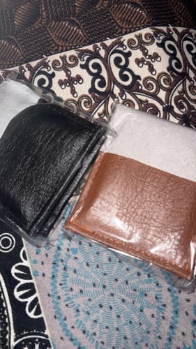 Reviewer's two ZIORO Spiderman wallets in plastic packaging, showing black and brown textured surfaces.
