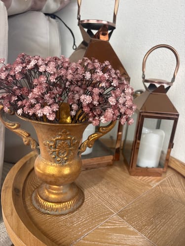 Customer's antique gold Lorenzo French Provincial Urn Vase filled with pink flowers on a wooden table with lanterns.