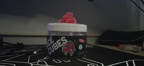 Customer's LEAFZ THC Space Cubes jar with red gummy cubes on the lid, sitting on a desk.