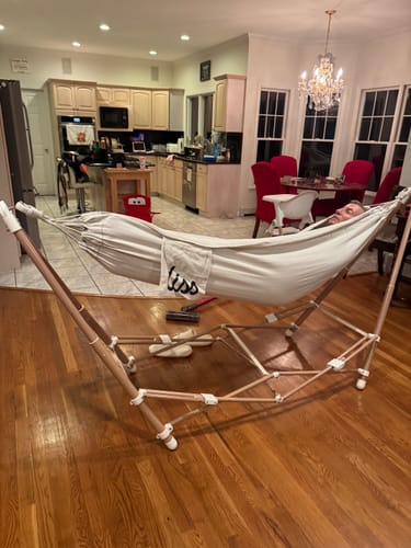 Customer's off-white The Go Hammock set up on its foldable frame in a brightly lit kitchen.