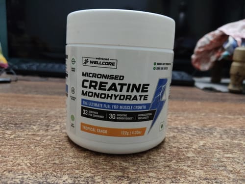Reviewer's jar of Wellcore Micronised Creatine Monohydrate Tropical Tango sitting on a wooden surface