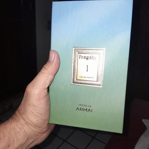 Customer's hand holding the rectangular box of Perfume Armaf Risala Fragaby 1, featuring a blue and green gradient.
