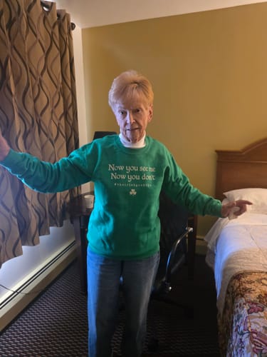 Customer's Irish Goodbye See Me Sweatshirt in green, worn by a person standing in a bedroom.