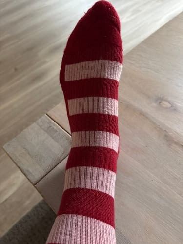 Kundens Diasocks støttestrømper i rød og lyserød stribet design, båret på en fod.
