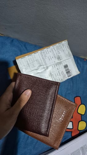 Customer's hand holding two maroon wallets without visible spider designs.