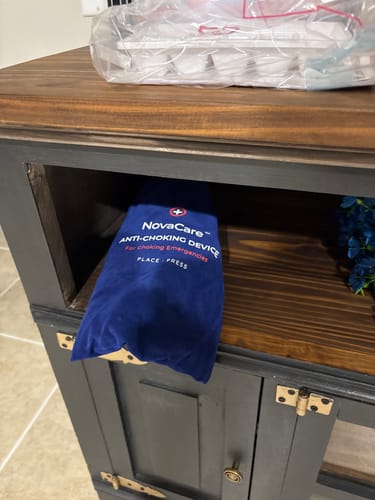 Customer's blue NovaCare Emergency Access Pouch resting on a wooden cabinet shelf in an entryway.