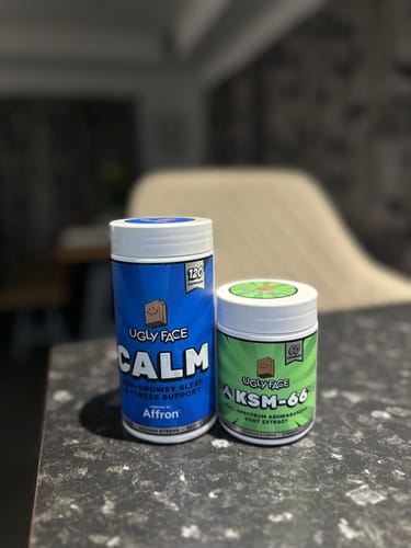 Customer's UGLYFACE CALM bottle and KSM-66 bottle sitting side by side on a grey patterned surface