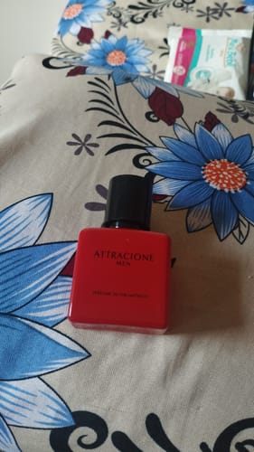 Customer's Attracione Men perfume bottle with a red container resting on a floral patterned surface.