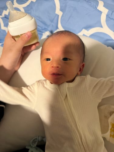 Customer's Hegen PCTO Collar and bottle held near a resting infant.