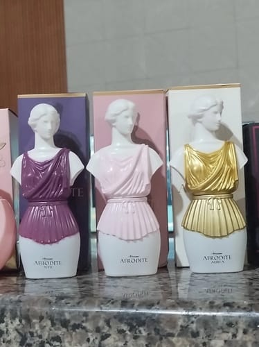 Customer's Kit Afrodite set showing three bust-shaped perfume bottles in purple, pink, and gold on a counter.