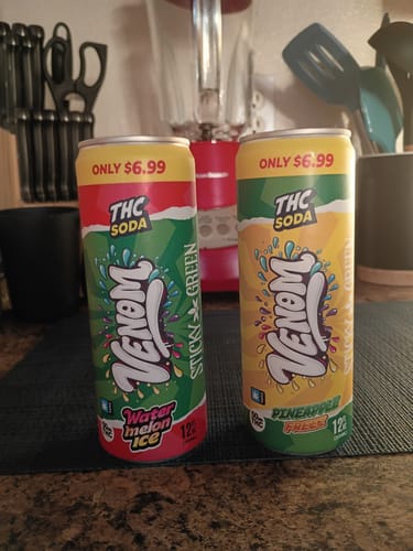 Customer's two tall cans of 100MG Infused Soda, Watermelon Ice and Pineapple flavors, on a kitchen surface.
