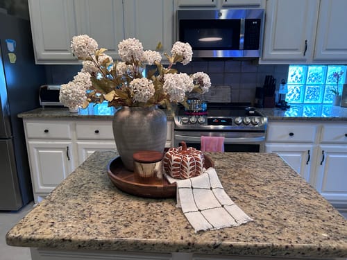 Customer's Faux Viburnum Flowers in a grey vase on a kitchen island, surrounded by a tray and pumpkin decor.