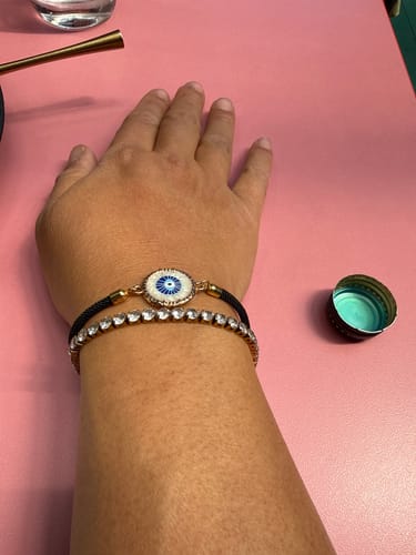 Reviewer's arm wearing a gold-toned Martina Classic Tennis Bracelet alongside an evil eye bracelet.
