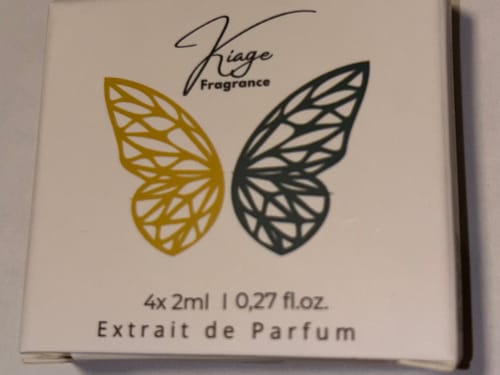 Kundenfoto des Tester Set Kartons mit einem gold-schwarzen Schmetterlingslogo und der Aufschrift Extrait de Parfum.