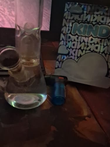 Customer's KIND Pineapple Express Minis packaging next to a glass water pipe and blue lighter on a dark surface.