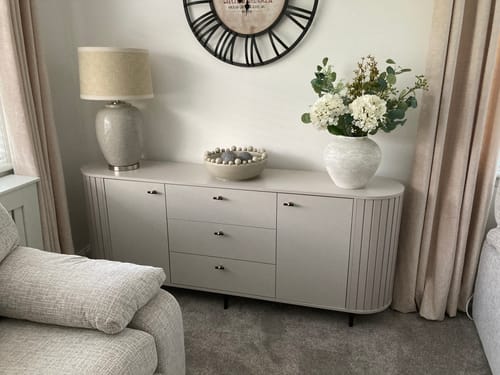 Customer's Arina Vase, in a stone finish, styled with white flowers on a sideboard.