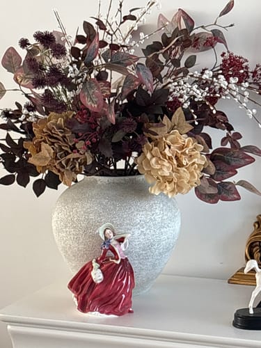 Reviewer's Burgundy Berries & Hydrangea arrangement in a textured vase, displayed with a small decorative figurine.