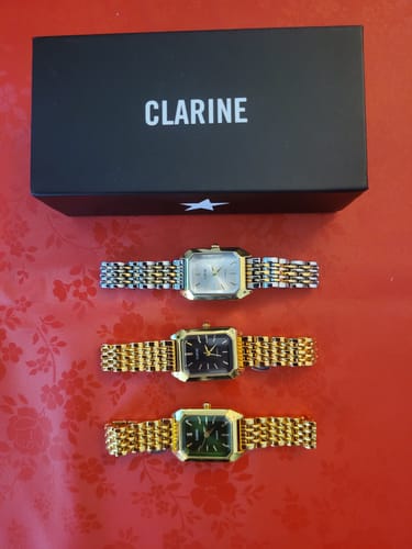 Customer's three Claire De Mains watches in gold and silver tones, positioned below a Clarine brand box.