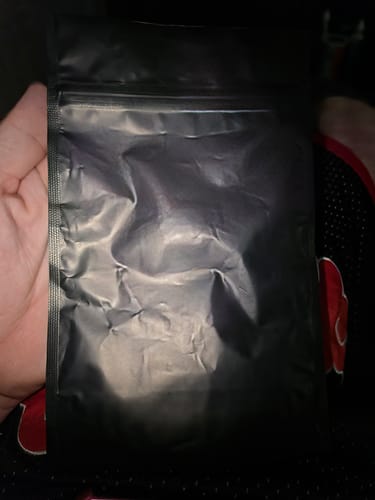 Customer's Package Protection by Covr arrives in a small, discreet, matte black shipping pouch held by a person.