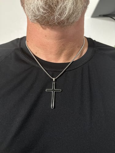 Customer's Onyx Cross necklace worn around the neck, featuring a black cross pendant on a simple metal chain.