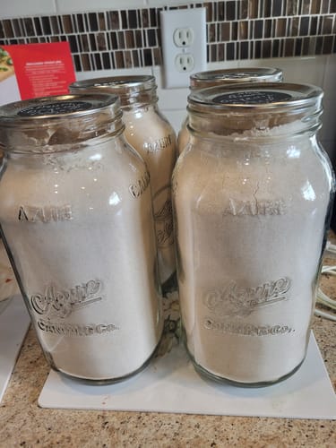 Customer's Mason Genie Vacuum Sealer Kit used to seal four glass jars filled with dry ingredients on a kitchen counter.