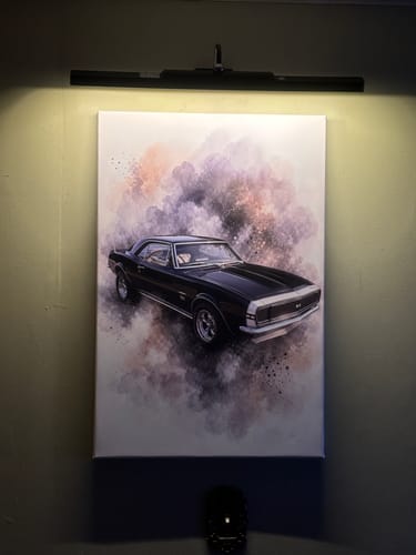 Customer's custom black car artwork canvas displayed on a wall in vertical orientation under a spotlight.