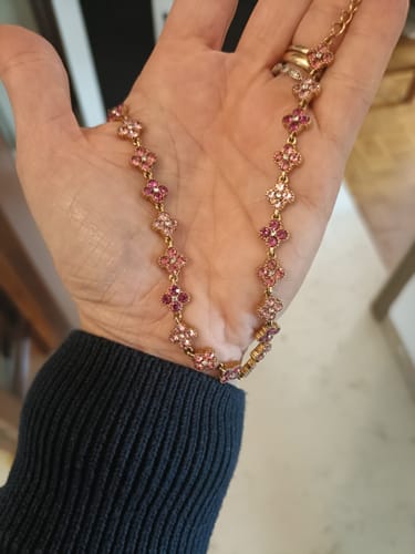 Customer's Collana Choker Fiori Rosa dorata con piccoli fiori e pietre rosa tenuta nel palmo di una mano.