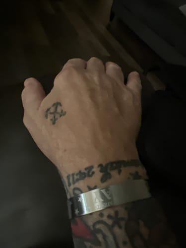 Customer's silver 22 A Day Memorial Bracelet worn on a tattooed wrist.