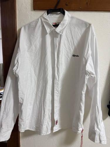 購入者のCleanfitオックスフォード長袖シャツ。ハンガーに掛けられており、胸の刺繍と裾の赤い紐が確認できます。