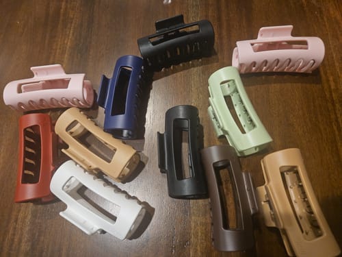 Reviewer shows a collection of stylish Mello hair clips in various colors on a wooden table.