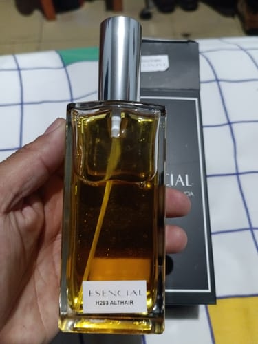 Un reseñador sostiene en su mano el frasco del perfume Esencial H293 Althaïr, con la caja del producto detrás.