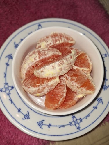 Ein Rezensent zeigt die geschälten Spalten der Cara-Cara-Orangen mit rosafarbenem Fruchtfleisch in einer Schale.