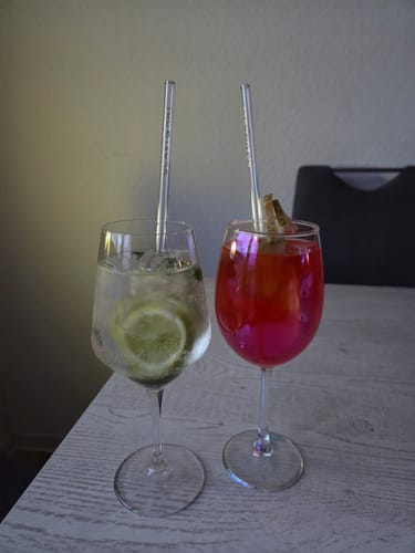 Ein Kunde zeigt die SCAVI & RAY Glasstrohhalme in einem klaren und einem roten Cocktail.