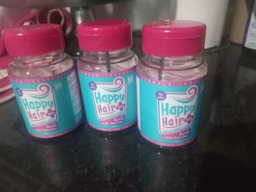 Cliente exibe os três potes do suplemento Happy Hair lado a lado em uma bancada.
