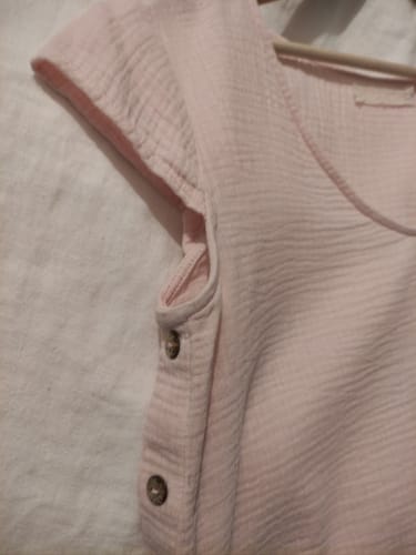 Gros plan par une cliente de la blouse Sidonie rose poudré, montrant le tissu texturé et les boutons latéraux.